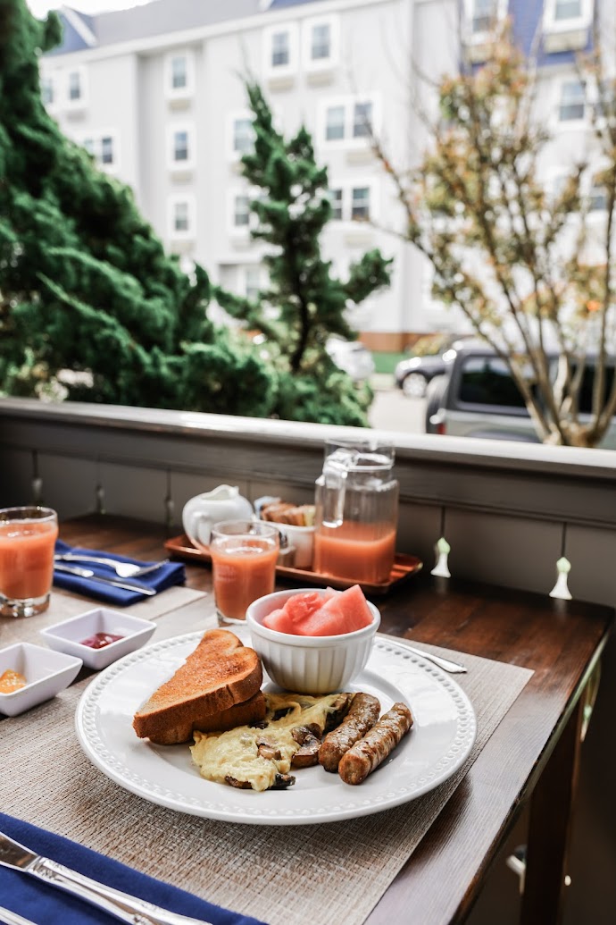 Eggs, toast, sausage and a side of fruit with juice